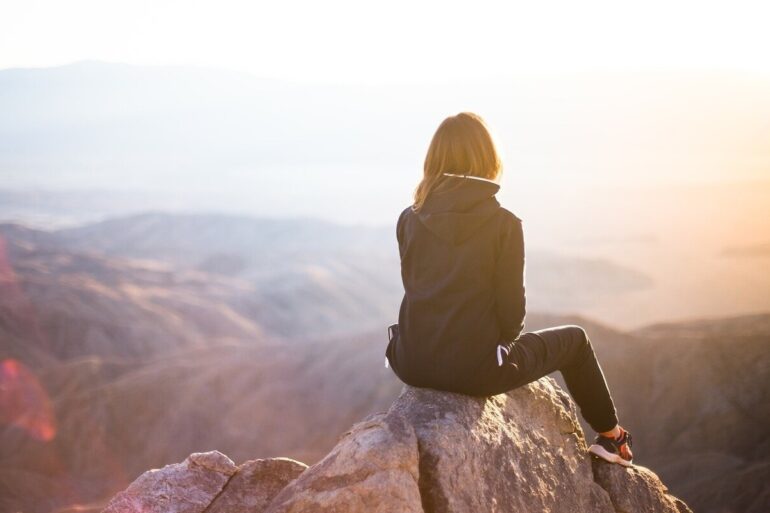 woman sitting on peak of a mountain
