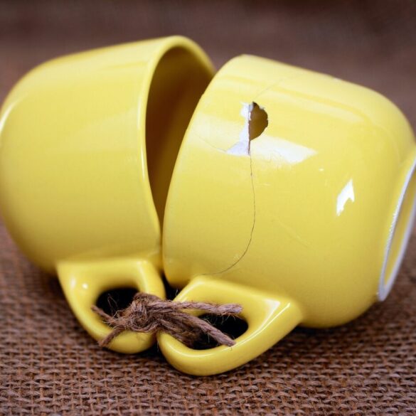 two yellow cups tied together, one broken