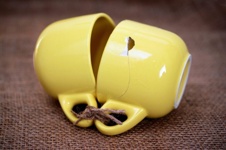 two yellow cups tied together, one broken
