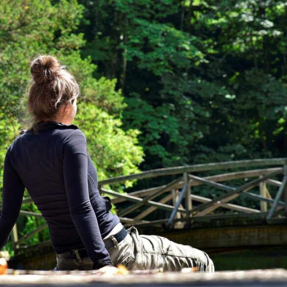 Young woman sitting on dock in front of bridge