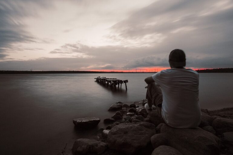 Man sitting calmly outdoors by water