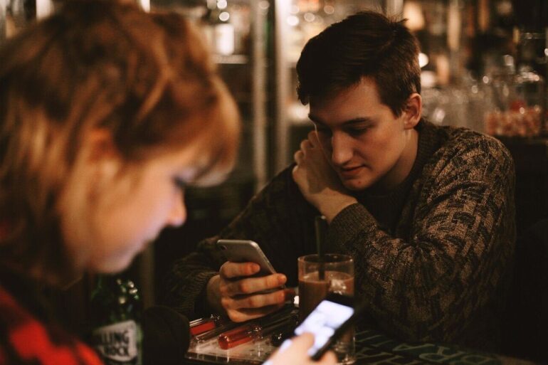 two people in restaurant both focused on their phones
