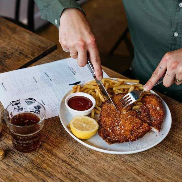 Man eating chicken and fries in restaurant