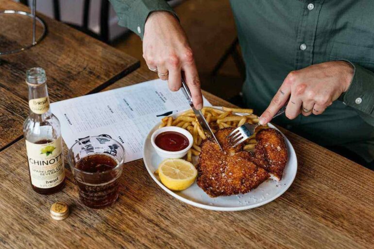 Man eating chicken and fries in restaurant