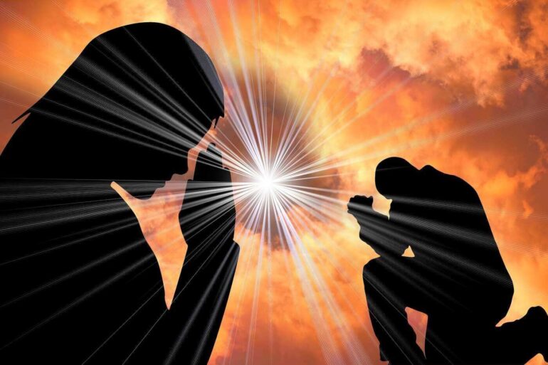 Silhouette of man and woman praying in front of light from sky