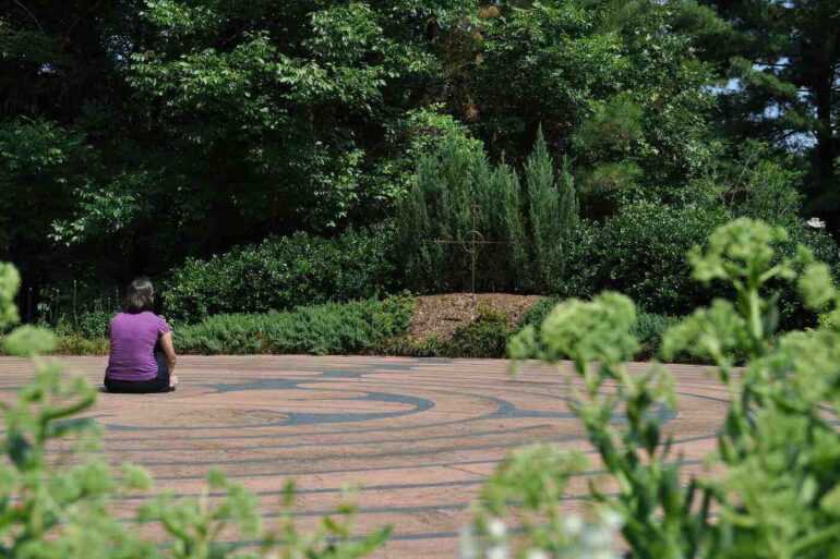 Woman sitting quietly on labyrinth, in front of metal compass