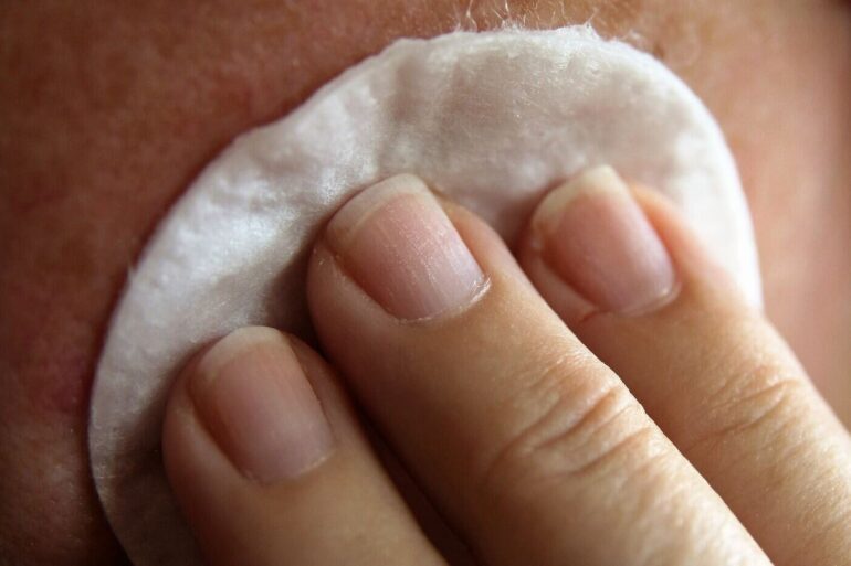 Person wiping face with soft skincare pad