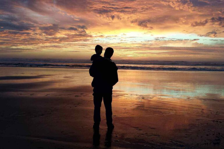 dad holding toddler at sunset