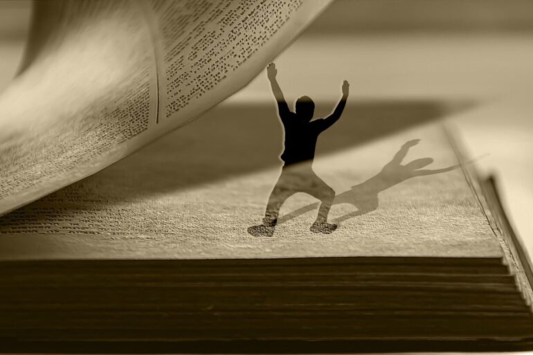 Small young man turning pages of large book