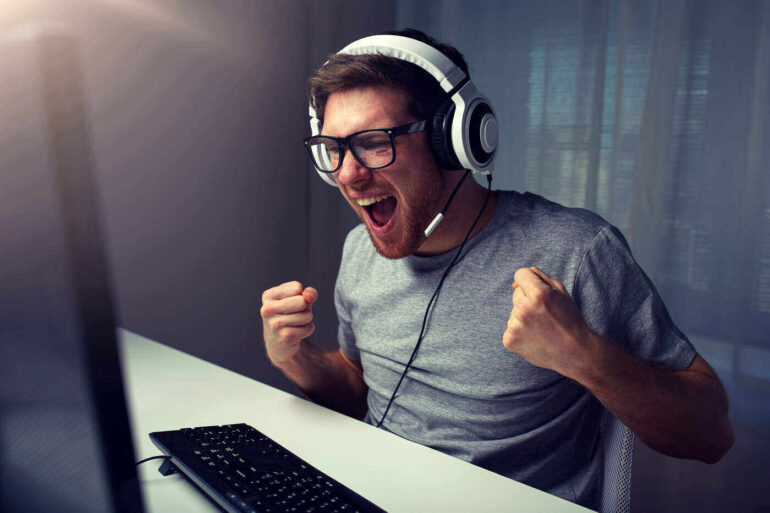 Man cheering in front of video game on computer