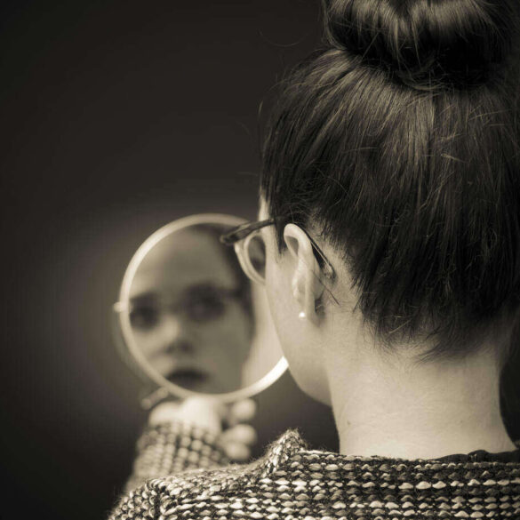 Woman looking reflectively at self in mirror