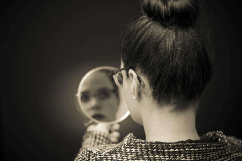 Woman looking reflectively at self in mirror