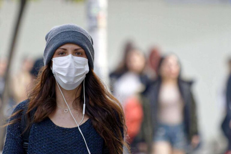 woman wearing mask surrounded by others without masks