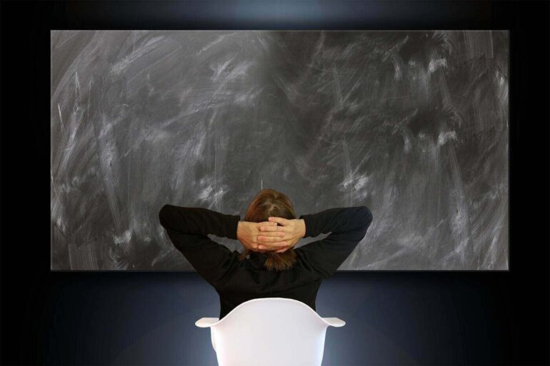 POST-PANDEMIC AND PUSHING 60: My old emigrant narrative no longer works 13 woman sitting in front of a blank blackboard