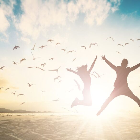 Silhouettes of couple jumping over water