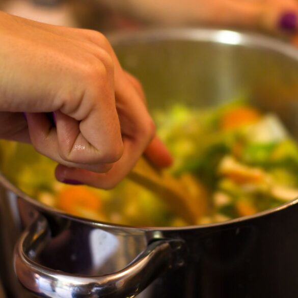 Person stirring vegetables in pot