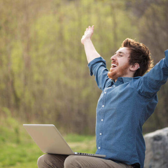 Happy man working on laptop outdoors