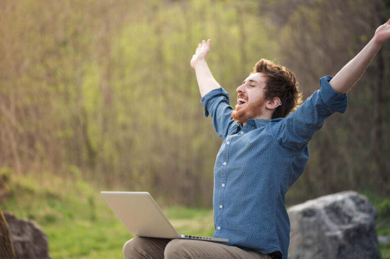 Happy man working on laptop outdoors