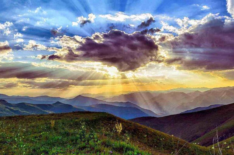 landscape with clouds with sun shining behind them