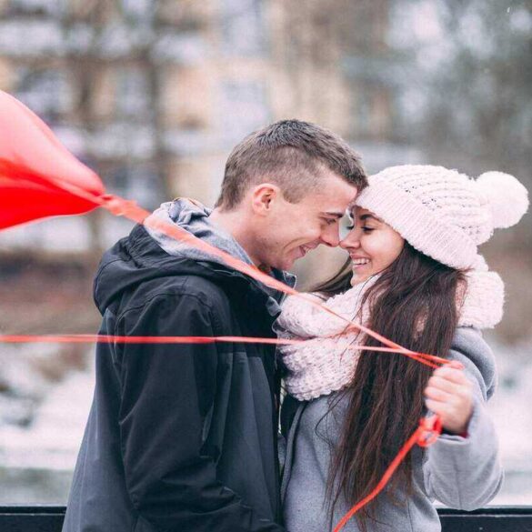 Couple in love hugging hand holding heart shaped balloons