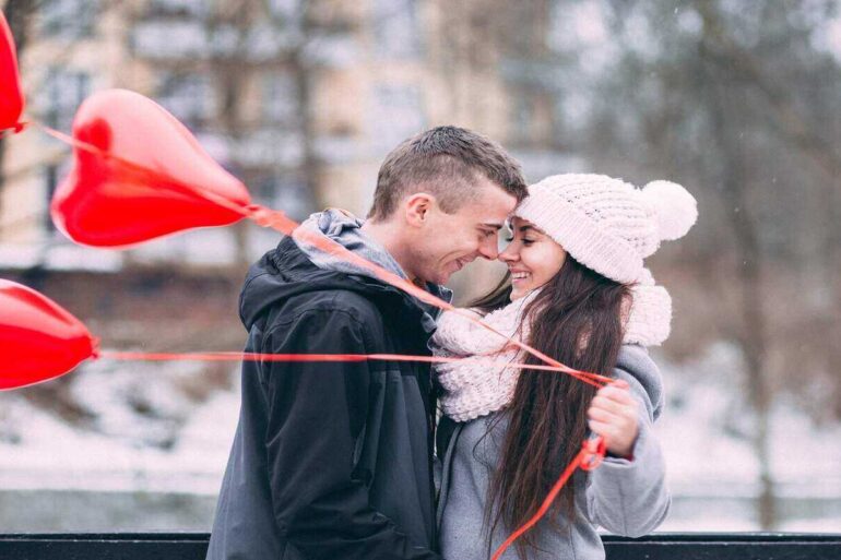 Couple in love hugging hand holding heart shaped balloons