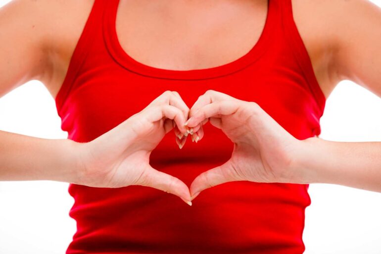 Person in tank top making heart shape with hands