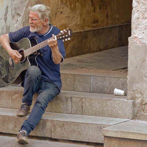 Old man playing guitar on cement steps