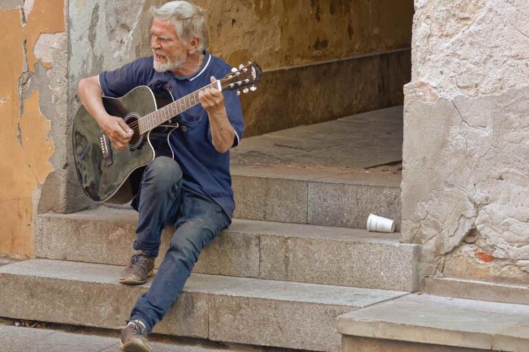 Old man playing guitar on cement steps