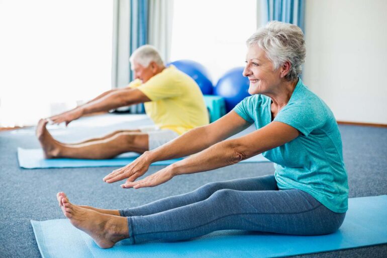 Two older adults doing Yoga stretches