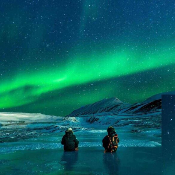 two people in the sea looking at the northern lights
