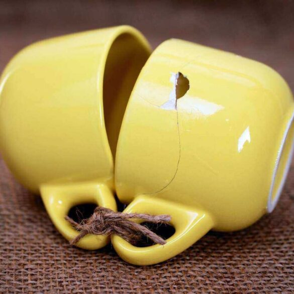 two cups tied together at the ears, one is broken