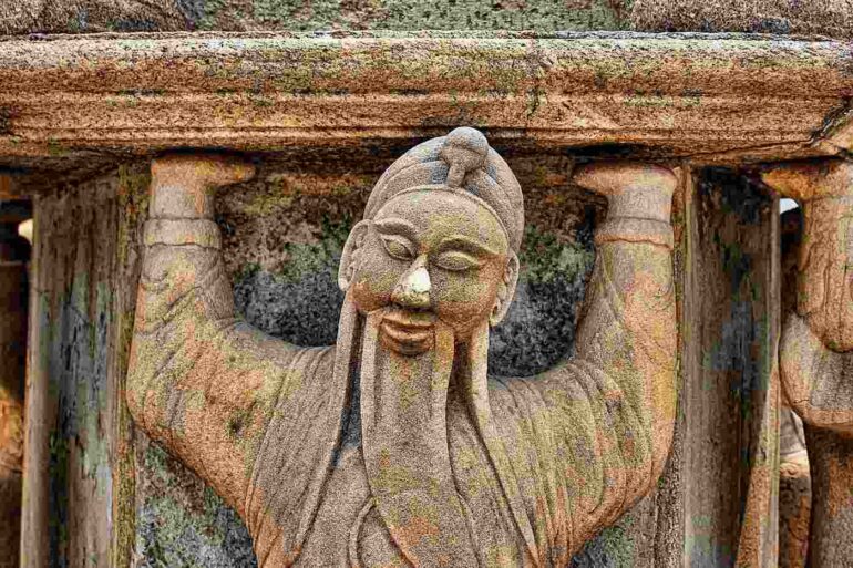 statue of monk holding up a lintel
