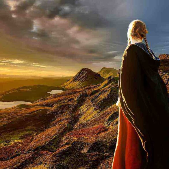 Girl in cape on a mountain watching the sun set