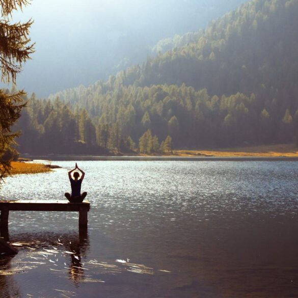 Woman doing Yoga on dock outdoors - How Mindfulness Helps People With Traumatic Brain Injuries