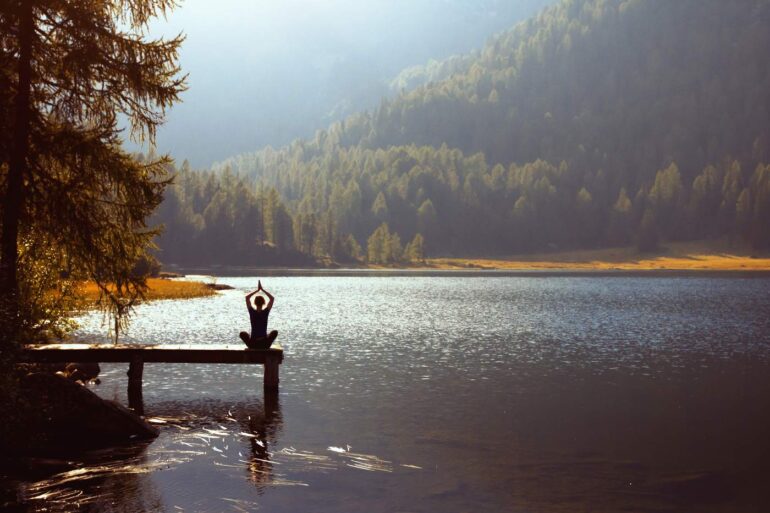 Woman doing Yoga on dock outdoors - How Mindfulness Helps People With Traumatic Brain Injuries