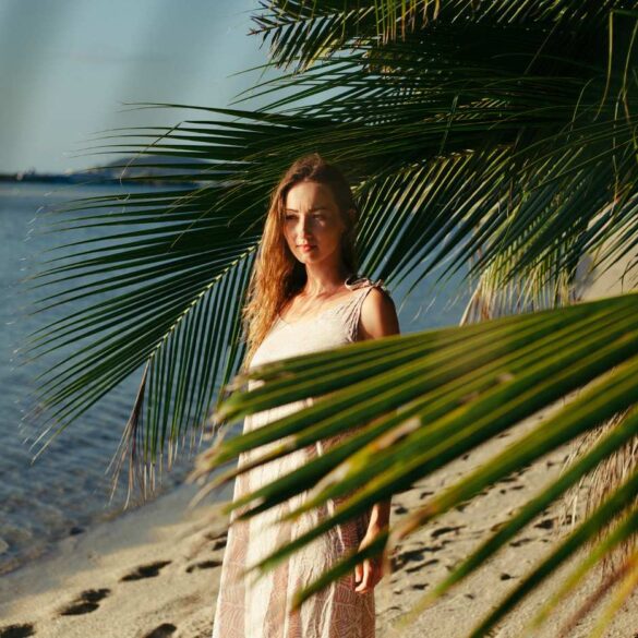 Young woman standing on sandy beach with palm trees - 5 Reflections on Living With Goodness, Exhilaration and More