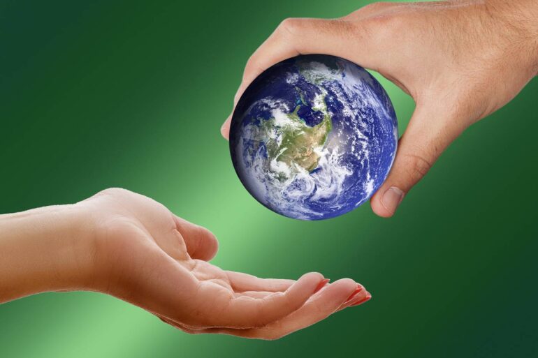Older hand hanging planet Earth to younger hand
