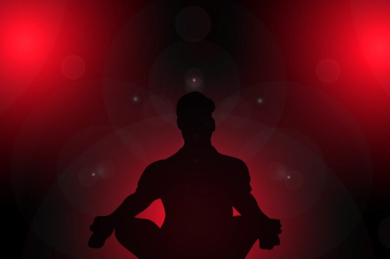 Silhouette of person meditating against red background