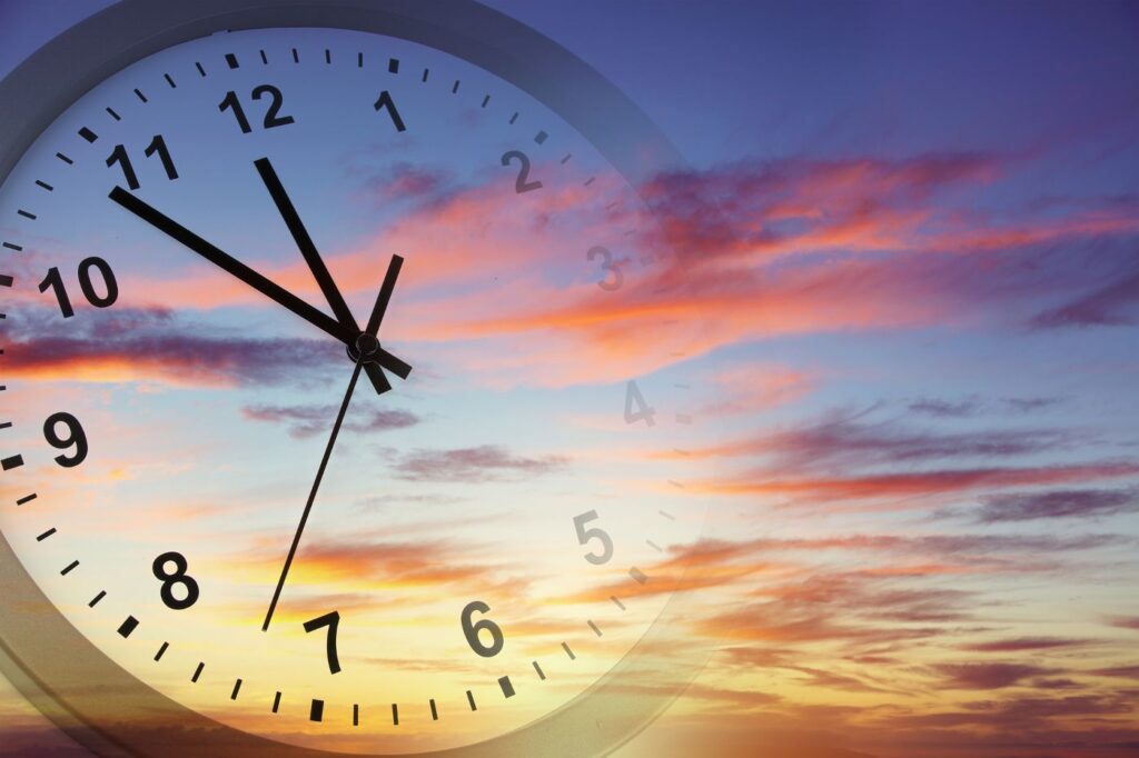 Clock floating in clouds at sunset