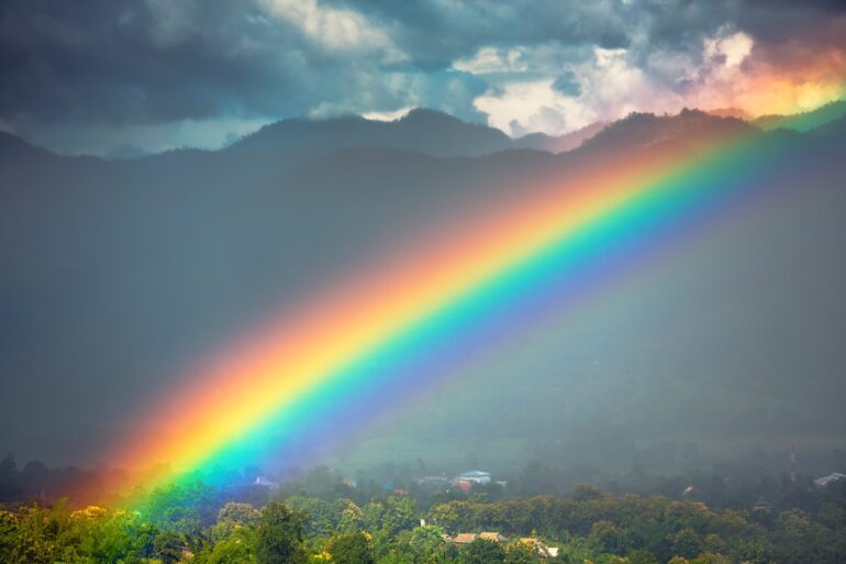 Rainbow across dark mountains with clouds above - Reflections About Stepping Forward With Balanced Emotions