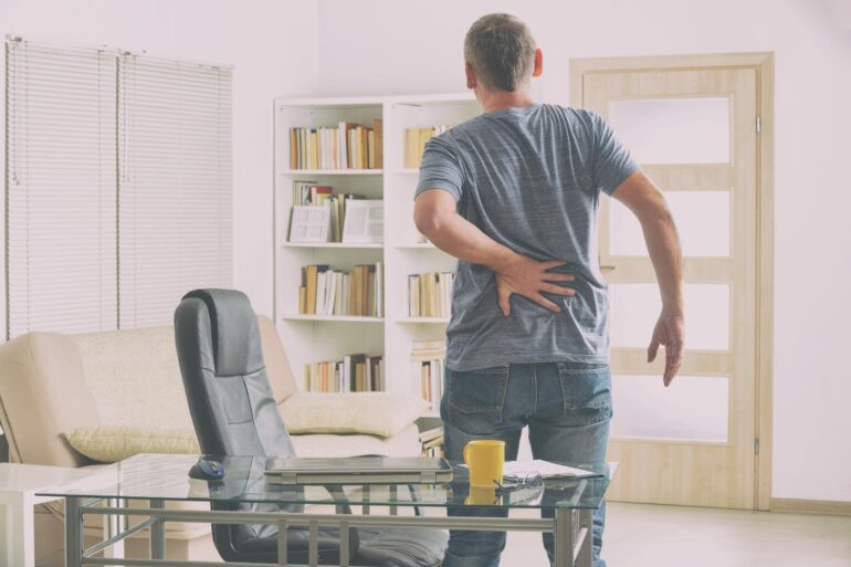 Man with back pain getting up from desk