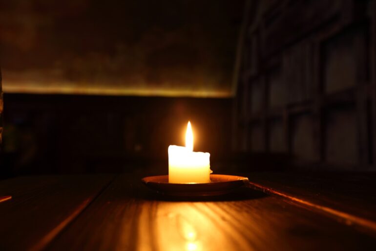 Lit candle in dark room - 5 Effective Ways of Coping With Shame Due to Addiction