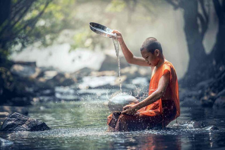 Young boy sitting in a stream, trickling water from a bowl - Spiritual Rituals For Busy People: 9 Mini-Rituals to Do Anywhere
