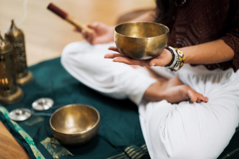 Person meditating with sound healing bowls - Insight Timer App: A Universal Hub for Meditation Practice
