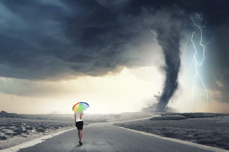 Woman walking in storm with rainbow umbrella - Overcome Every Storm in Life With Love and Gratitude