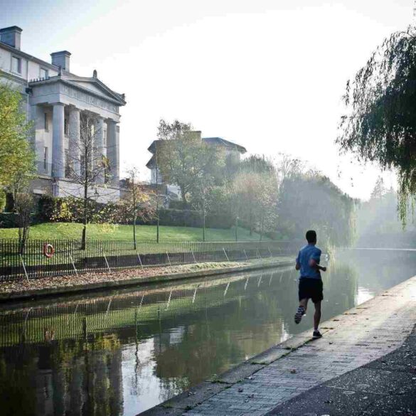 Man running on a pavement next to a water channel