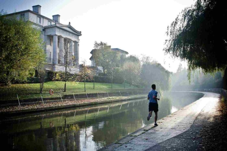Man running on a pavement next to a water channel