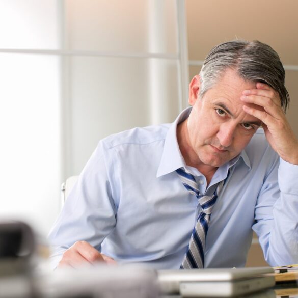 Annoyed middle-aged man at desk - We Are Not Our Thoughts—But We Can Observe Them Mindfully