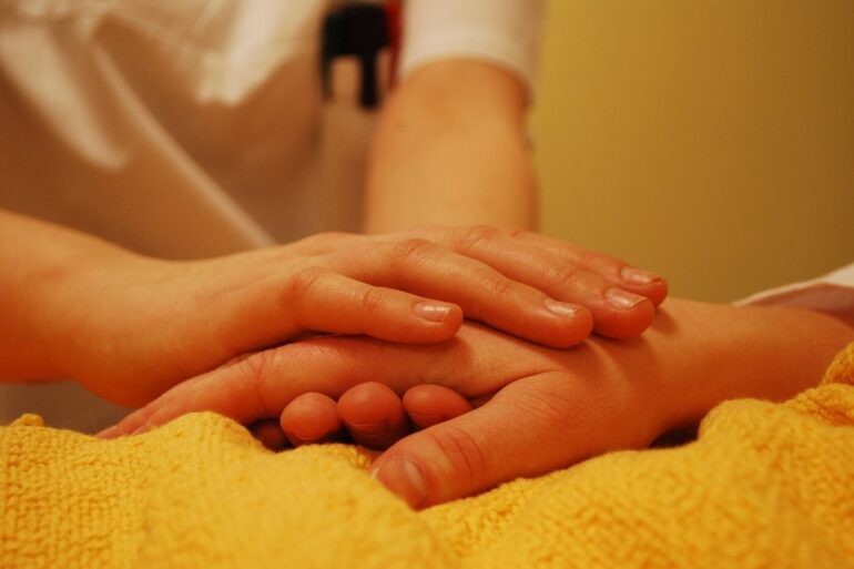Comforting hand holding for a sick person in bed - We Need Each Other: Lessons Learned While Living With COVID