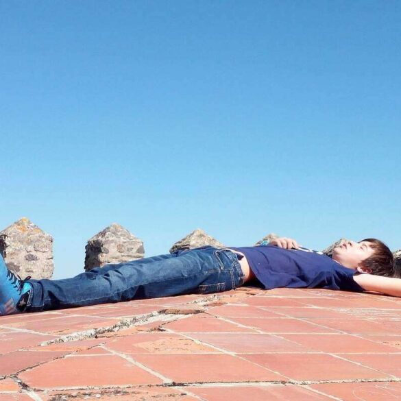 man lying on a stone wall looking at the sky - Stoic in Training: It’s About Acceptance, Not Indifference